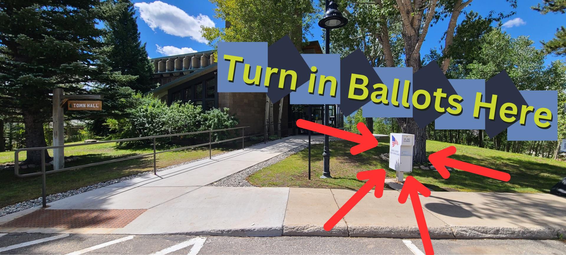 A picture of Dillon Town Hall with a sign that says Turn in Ballots Here and some arrows pointing at the ballot drop box